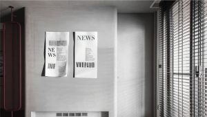 Minimalist interior with textured grey walls and abstract newspaper-style wall art.
