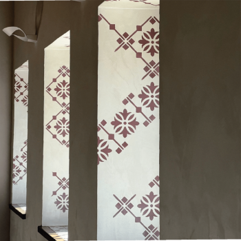 Lime-based wall finish with geometric floral patterns in burgundy, applied by specialty contractors, enhancing the architectural design of an interior space.
