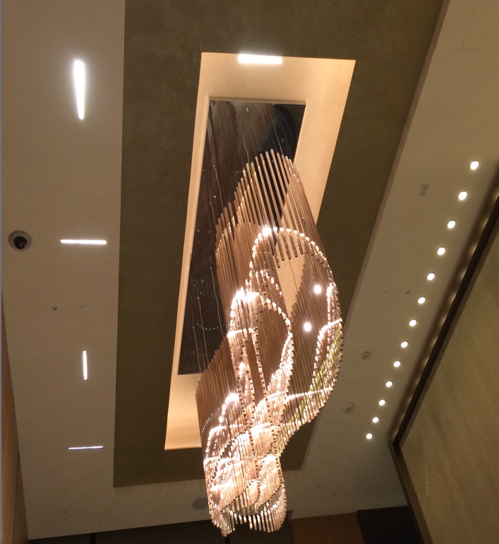 Luxurious chandelier with cascading crystal strands and warm lighting in a modern ceiling design.
