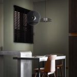 Modern dining space with a muted green lime-washed wall and industrial-style furnishings.