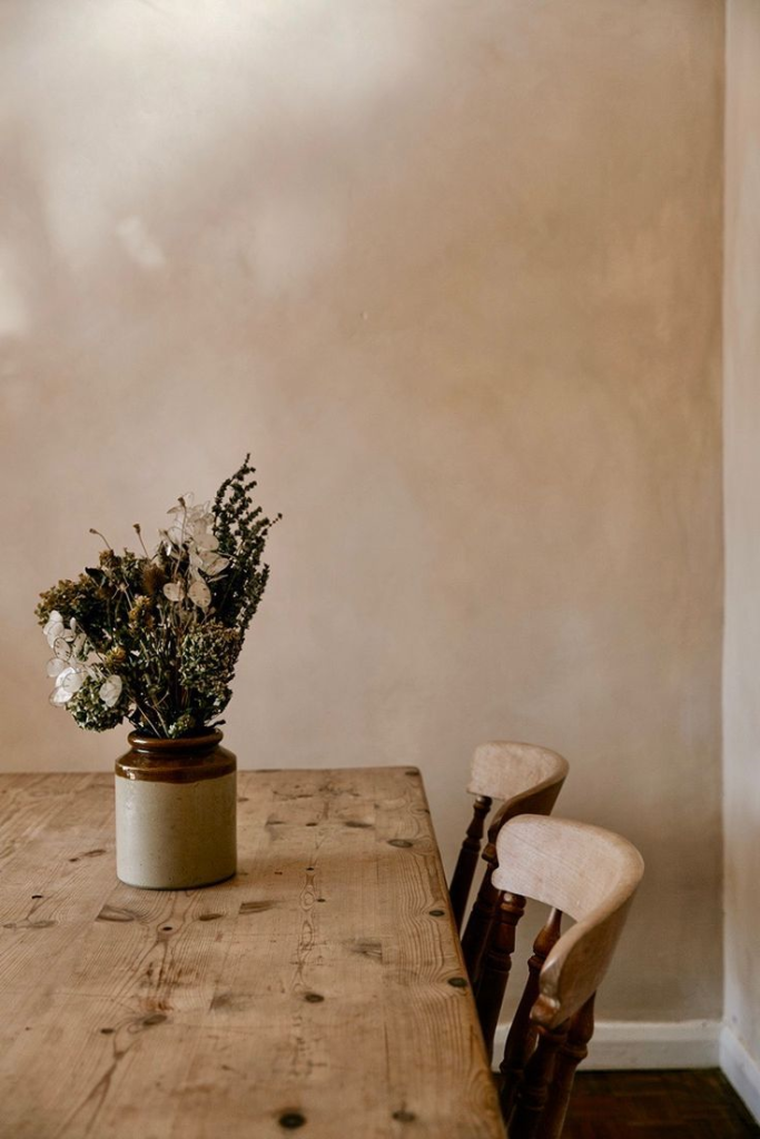 Wooden Table with Vase of Dried Flowers and Chairs