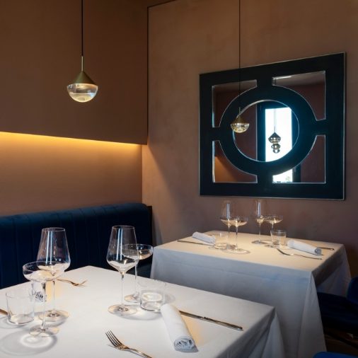 Elegant dining setup featuring lime-based painted walls, cozy blue seating, and sophisticated table arrangements.