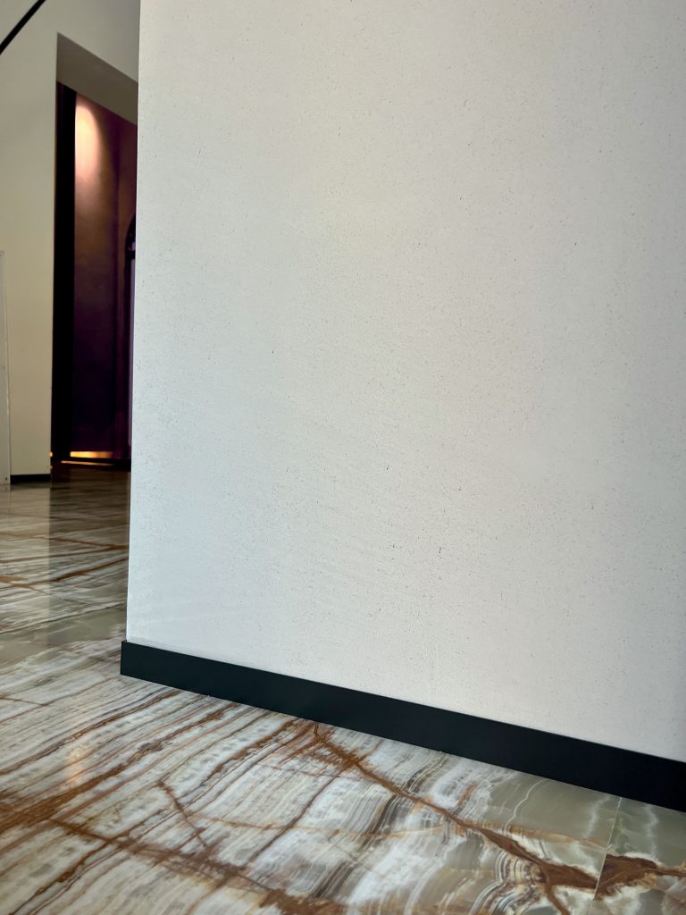 Close-up of a white wall with black trim and marble flooring