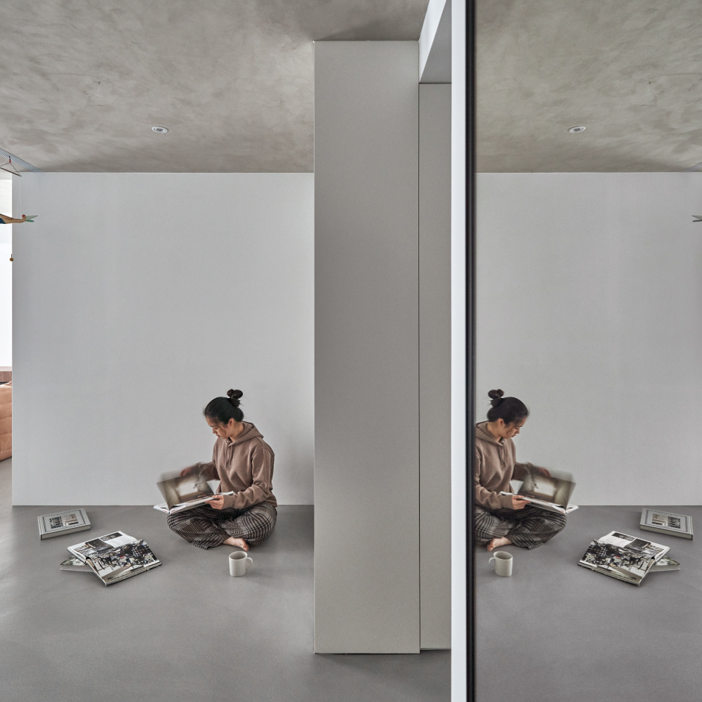 Person Reading a Magazine in a Minimalist Interior with Reflections
