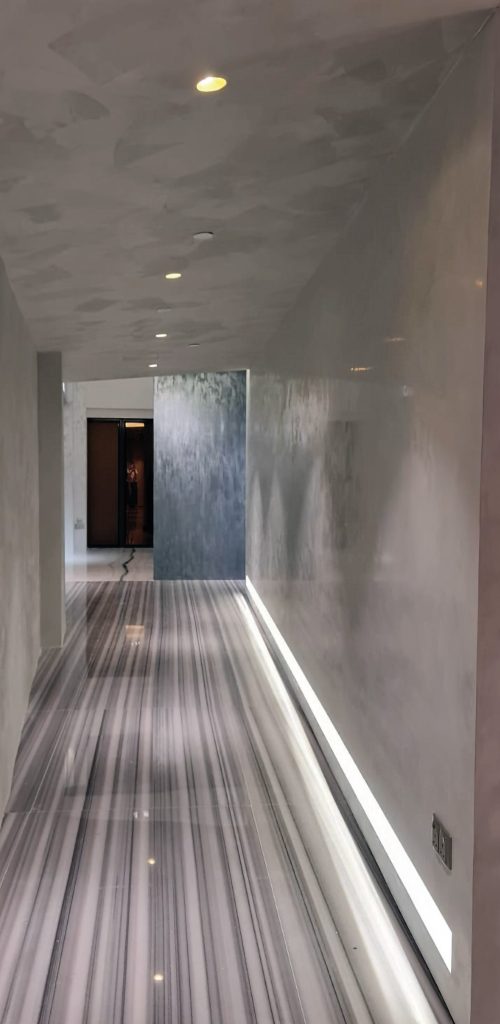 Luxury corridor with ISPEGU Stucco Lustro high-gloss lime plaster walls, marble flooring, and hidden LED lighting