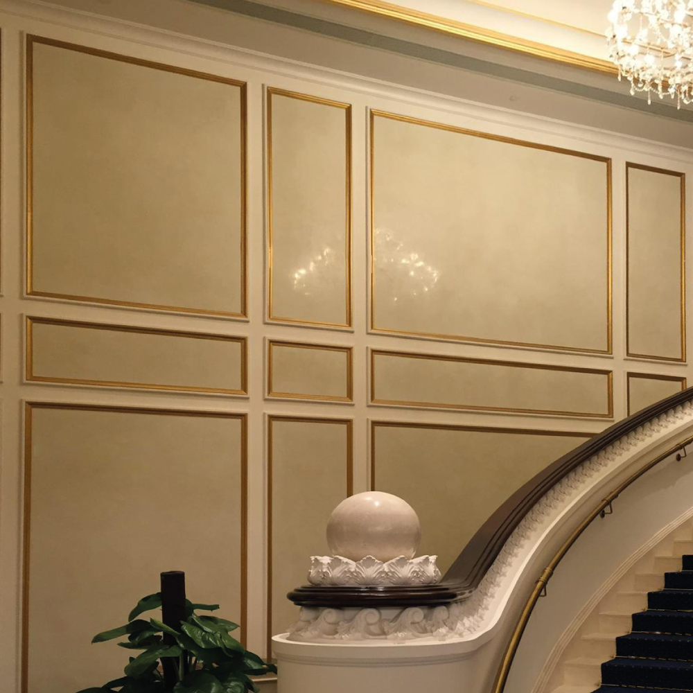Ornate staircase with gilded wall panels and decorative marble pillar