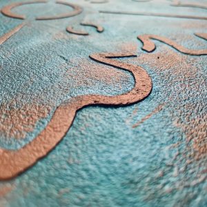 Close-up of a textured turquoise wall featuring a raised, organic stencil design in earthy tones by Decora.