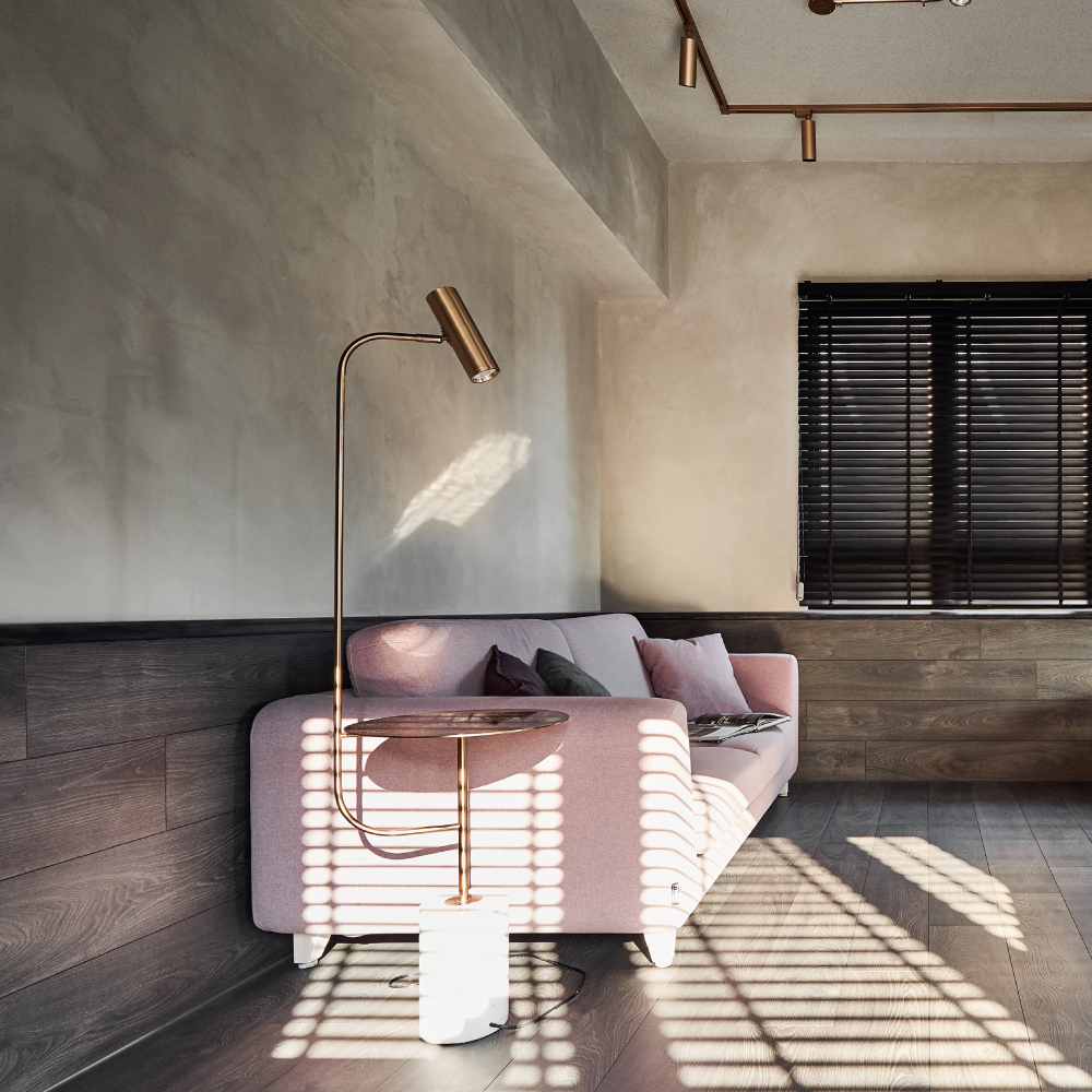 Cozy living room with a pink sofa, modern floor lamp, and textured lime-based wall paint, showcasing an inviting ambiance.