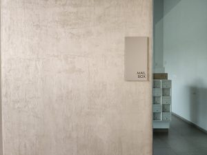 A textured wall with a mail box sign, showcasing a blank canvas that can be enhanced with lime-based paintings by specialty contractors.