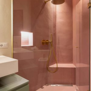 Modern pink walk-in shower featuring lime-based plaster walls with gold fixtures, expertly finished by specialty contractors.