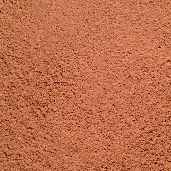 Close-up of terracotta-colored textured stucco wall surface.