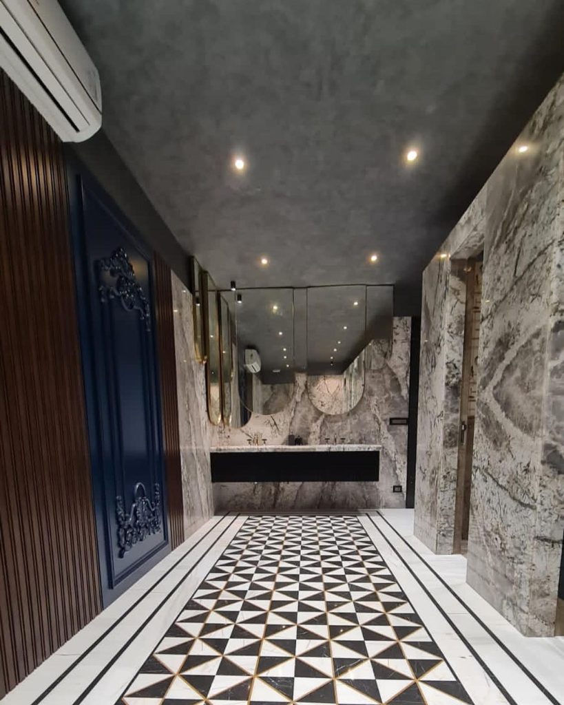 Modern luxury restroom with Decora’s textured metallic ceiling finish, marble walls, and geometric patterned flooring.