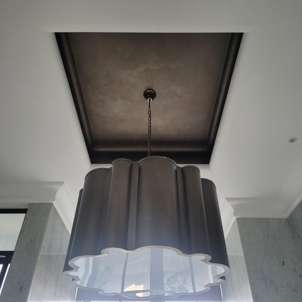 Luxury ceiling detail finished with Decora Infinity metallic paint showcasing a velvety, reflective metallic wall coating above a statement chandelier.
