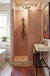Soft rose tadelakt shower walls with brass fixtures by Decora A&C