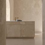 Teseo Travertine satin finish walls and cabinetry by Decora A&C in soft neutral tones with arched architectural details.