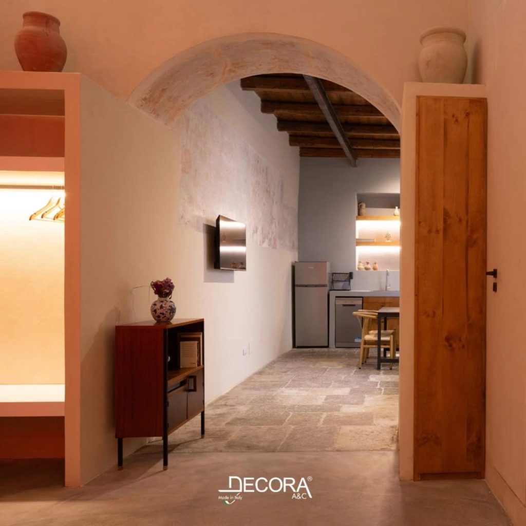 Interior view of a warm, modern space with Microcement Diamond System flooring, exposed wooden beams, and a cozy kitchen area.