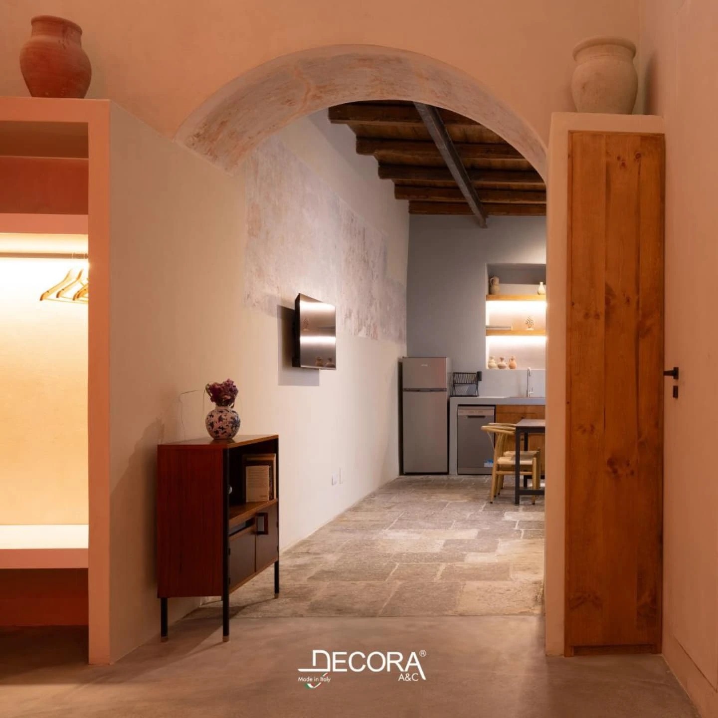 Interior view of a warm, modern space with Microcement Diamond System flooring, exposed wooden beams, and a cozy kitchen area.
