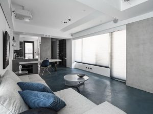 Living room with Decora Diamond System microcement floor in deep blue and minimalist grey walls, styled with modern furniture.