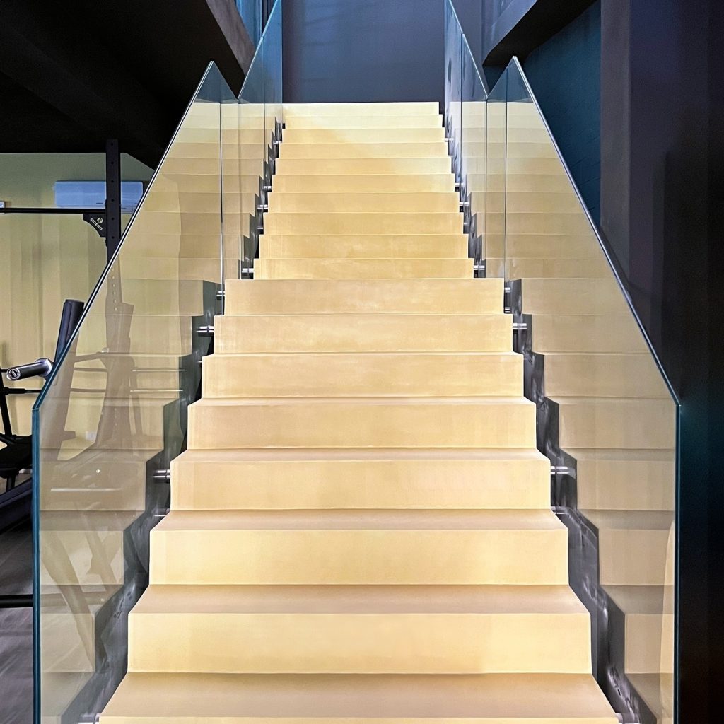 Decora Microcement staircase with seamless surface and modern glass balustrade in luxury interior