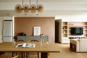Modern living and dining area with a silk lime wash feature wall, wood table, open shelving, and minimalist decor