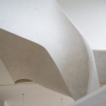 Elegant curved staircase coated with Tatto and Incanto lime plasters, showcasing seamless application and soft, natural light reflection