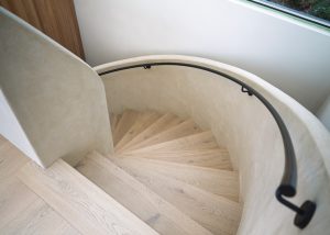 Minimalist interior staircase finished in Decora’s Tatto and Incanto lime plasters, highlighting smooth curves and natural light play