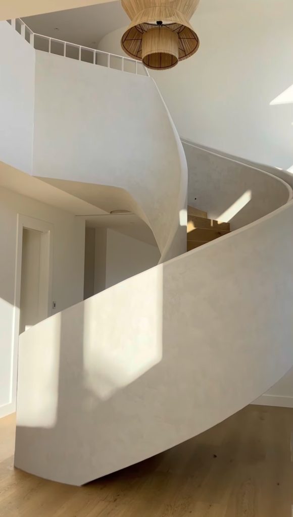Sculptural staircase with seamless lime plaster finish in neutral tones, designed for modern minimalist interiors using Decora’s natural materials