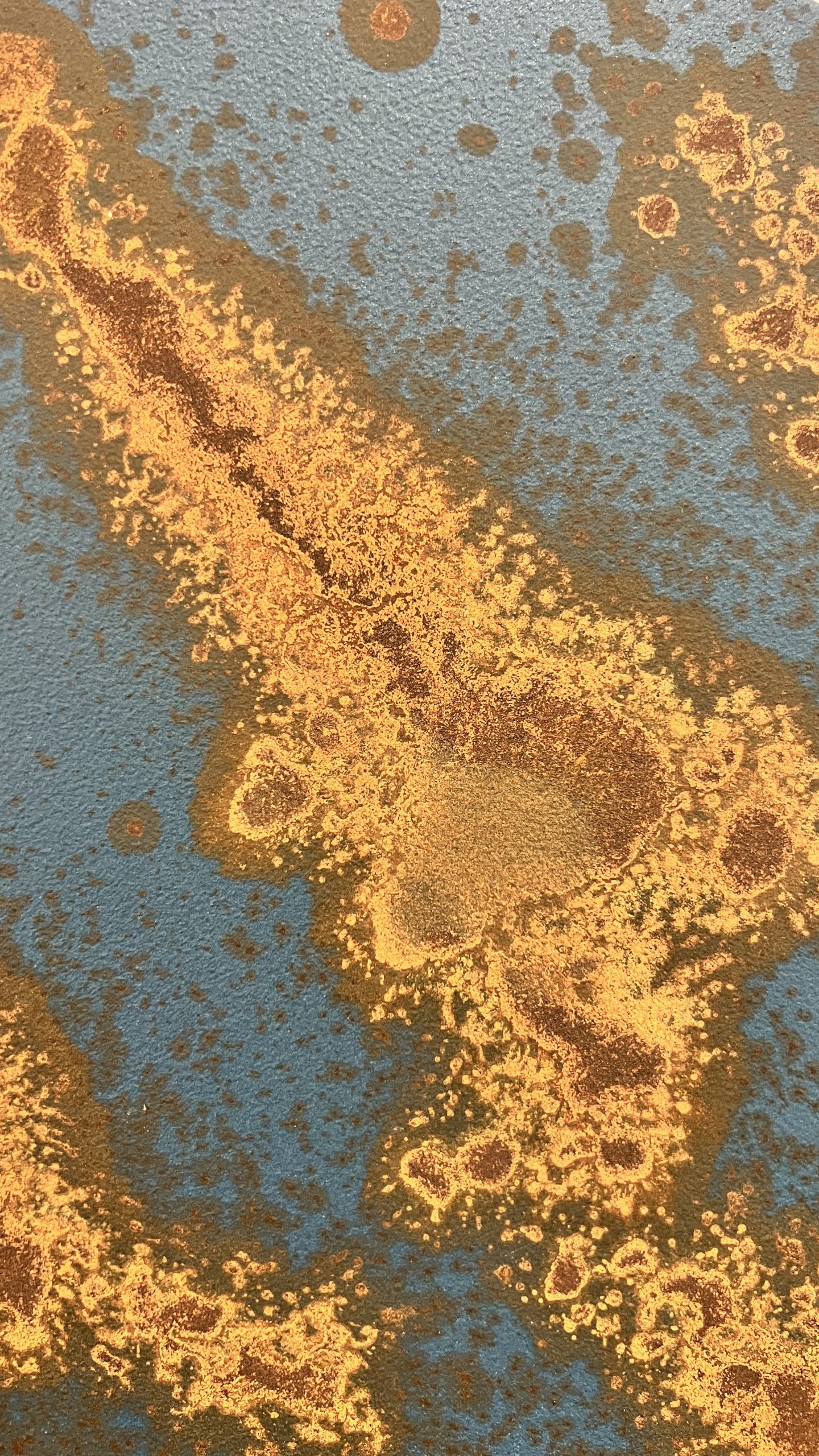 Rusty orange oxidation flowing over a steel blue metallic background, created with Rust.IT decorative paint.