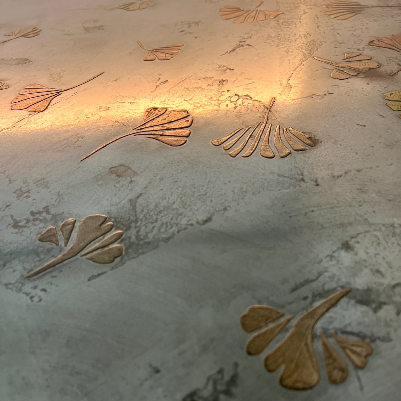 Detailed view of metallic steel art with organic, subtle patterns in warm beige and gold tones.
