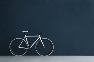 Minimalist room with white bicycle against a deep navy wall coated in Italian slaked lime paint by Decora A&C