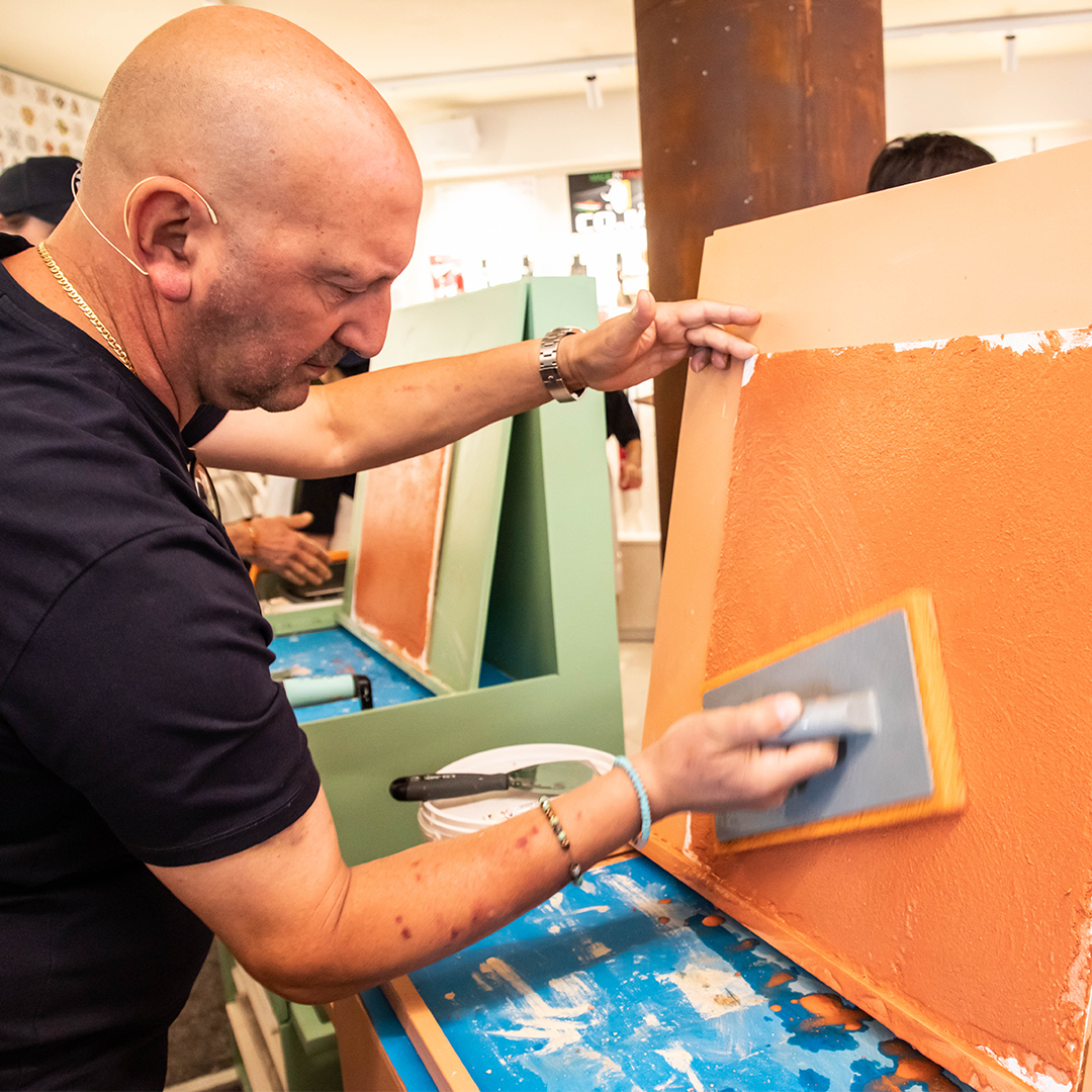 Luigi applying Venetian plaster at Decora Academy, demonstrating expert craftsmanship on a colorful surface.