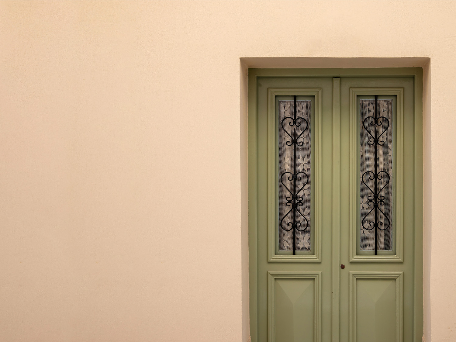 Exterior wall finished with Acryshield weatherproof acrylic coating beside a vintage green door with decorative wrought-iron details.