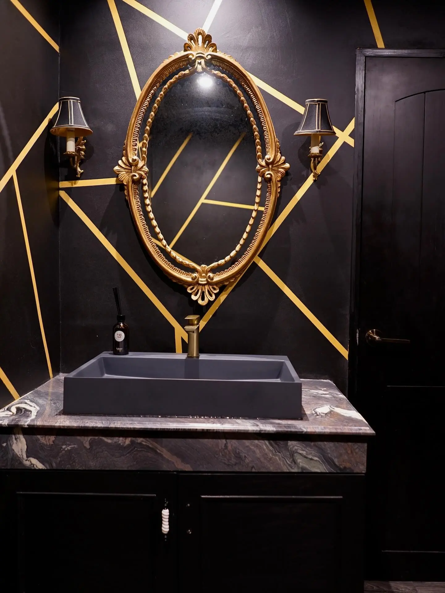 Luxury bathroom wall finished with black microcement and gold geometric accents, showcasing high-end Italian decorative finishes and Sicilian craftsmanship.