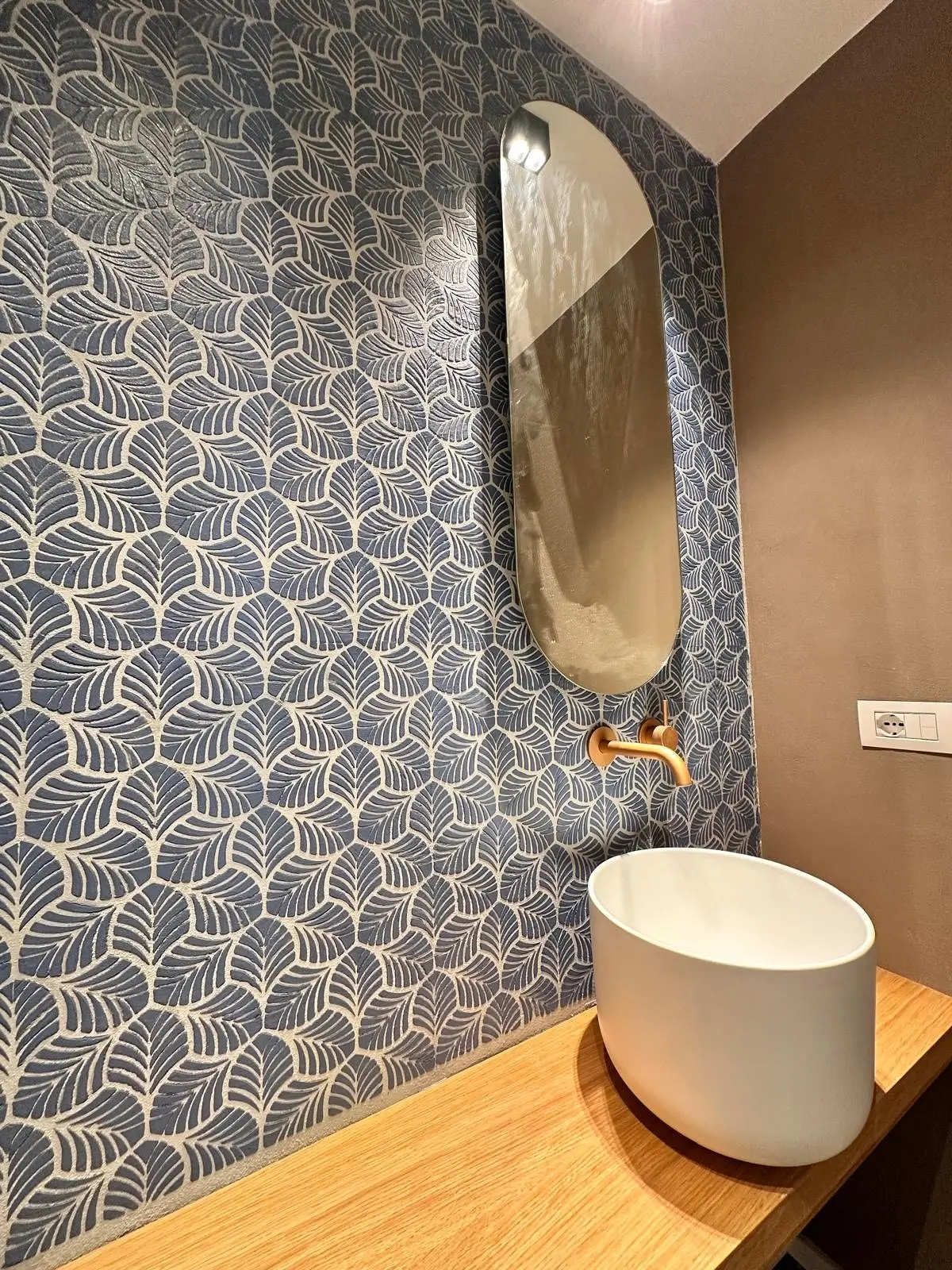 Elegant bathroom wall featuring Italian decorative finishes with a leaf-patterned stencil, showcasing luxury Sicilian craftsmanship.