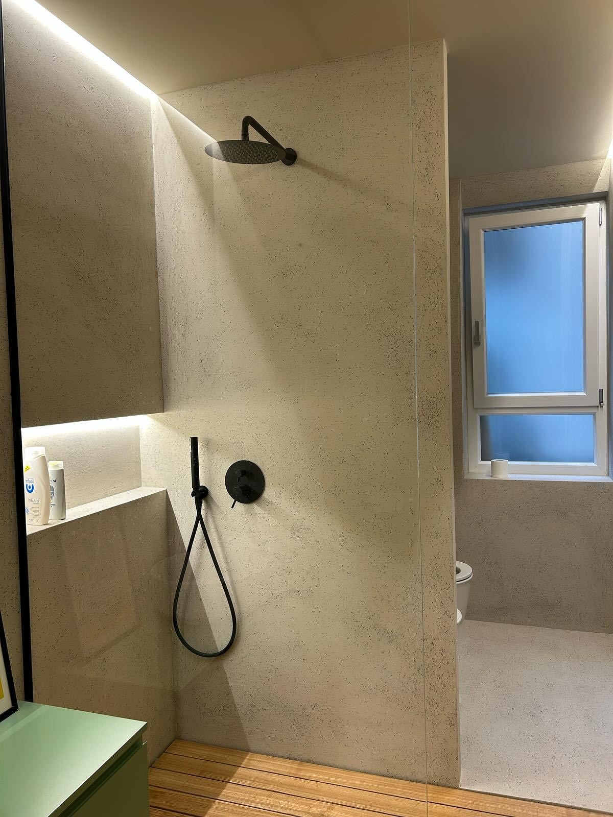 Minimalist shower featuring a sleek micro-cement wall and floor with Decora A&C's Diamond System, complemented by modern fixtures and lighting.