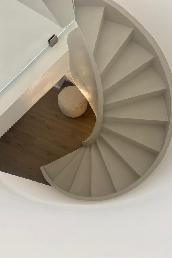 Close-up view of a circular staircase with lime-based paint and wooden flooring.