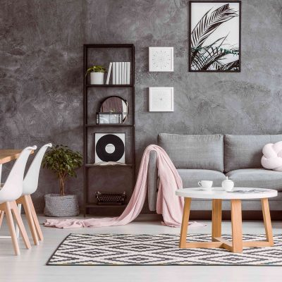 Modern living room with a gray textured wall, Scandinavian-style decor, and pastel accents.