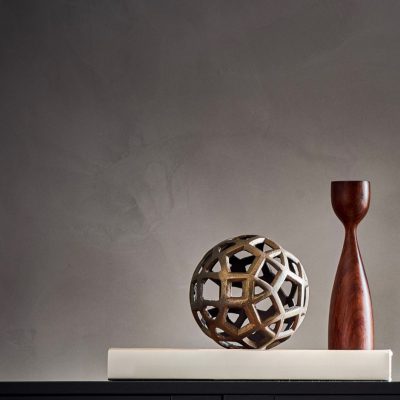 Minimalist decor with geometric metal sphere and wooden sculpture on a modern shelf.