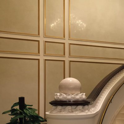 Elegant staircase with a gold-trimmed wall in a luxurious interior setting.
