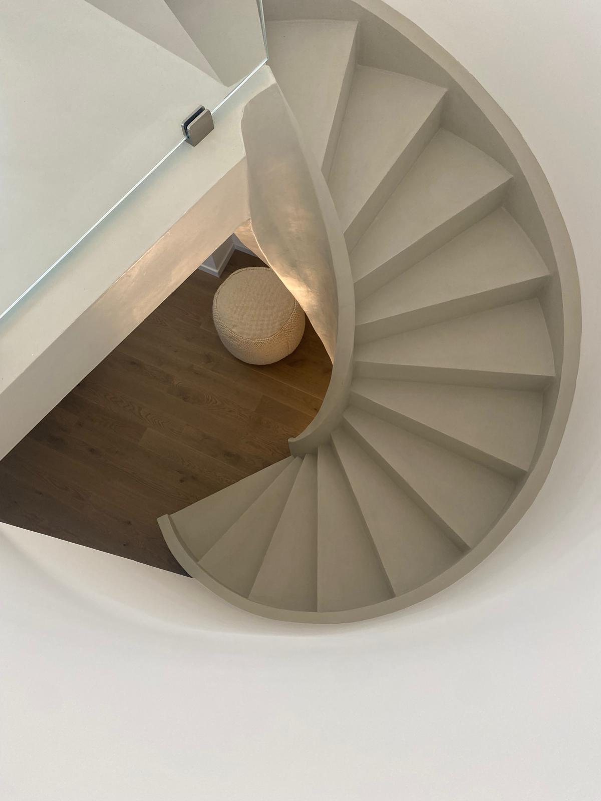 Close-up view of a circular staircase with lime-based paint and wooden flooring.